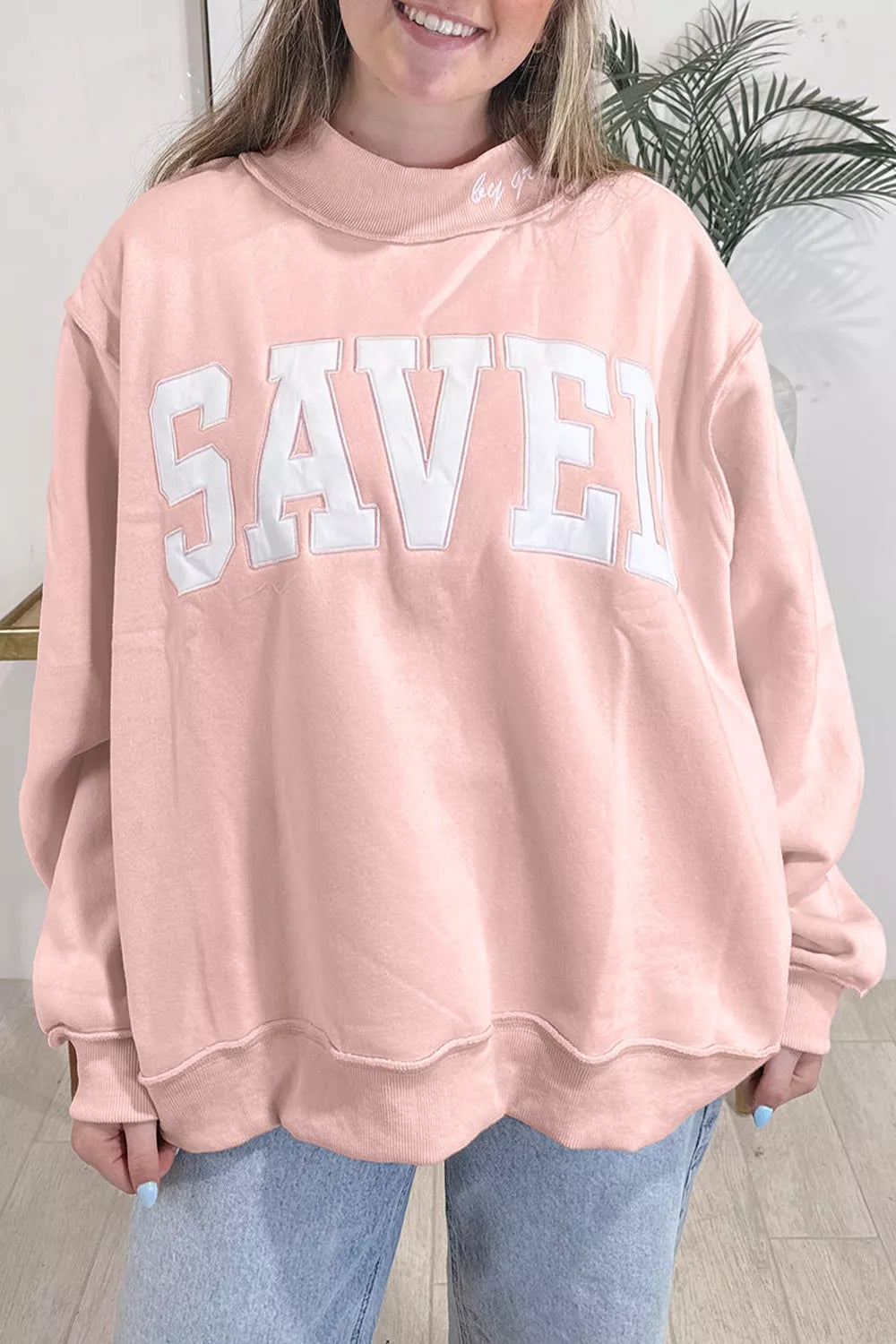 Pink SAVED graphic sweatshirt, front view styled with jeans