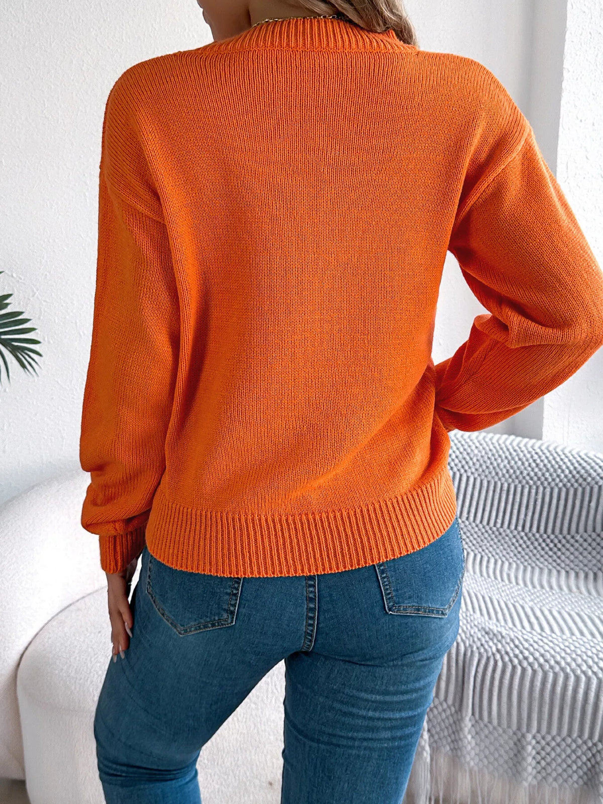 Orange halloween pumpkin face knit sweater, back view.