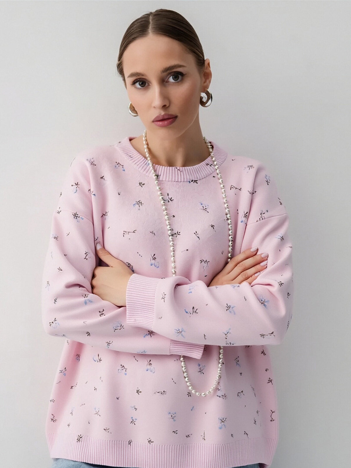 Pink floral dropped-shoulder oversized sweater, front with arms crossed.