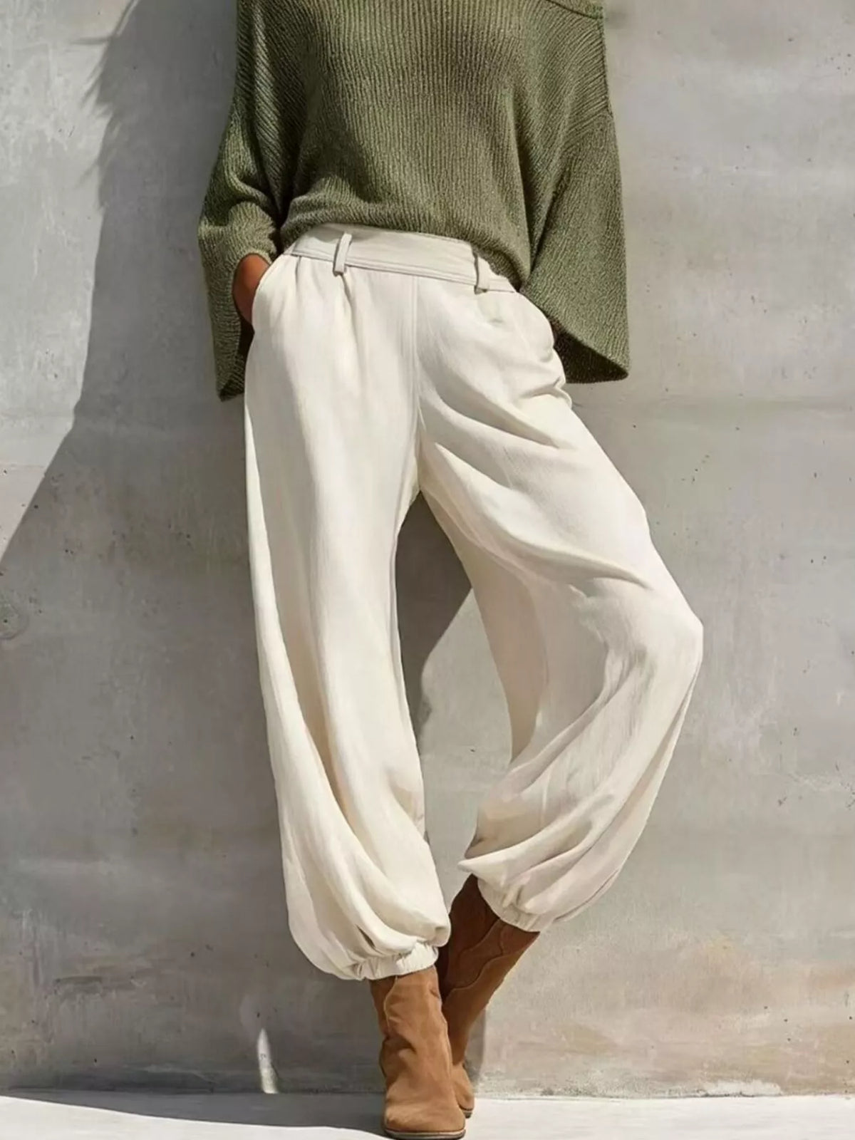 Green one-shoulder knit top and pants set, white pants front view.