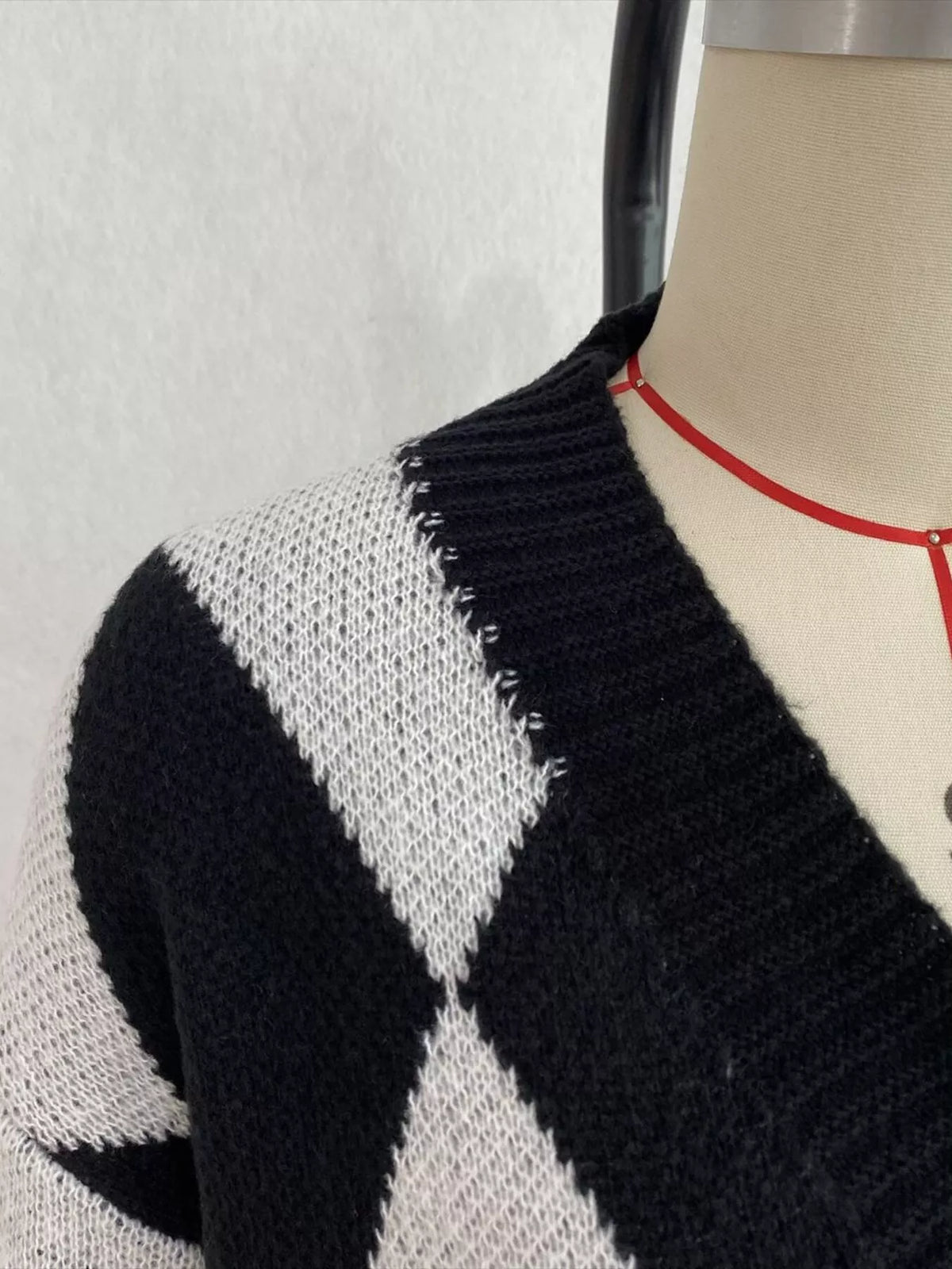 Black and white argyle v-neck button-front cardigan, neckline and knit detail.