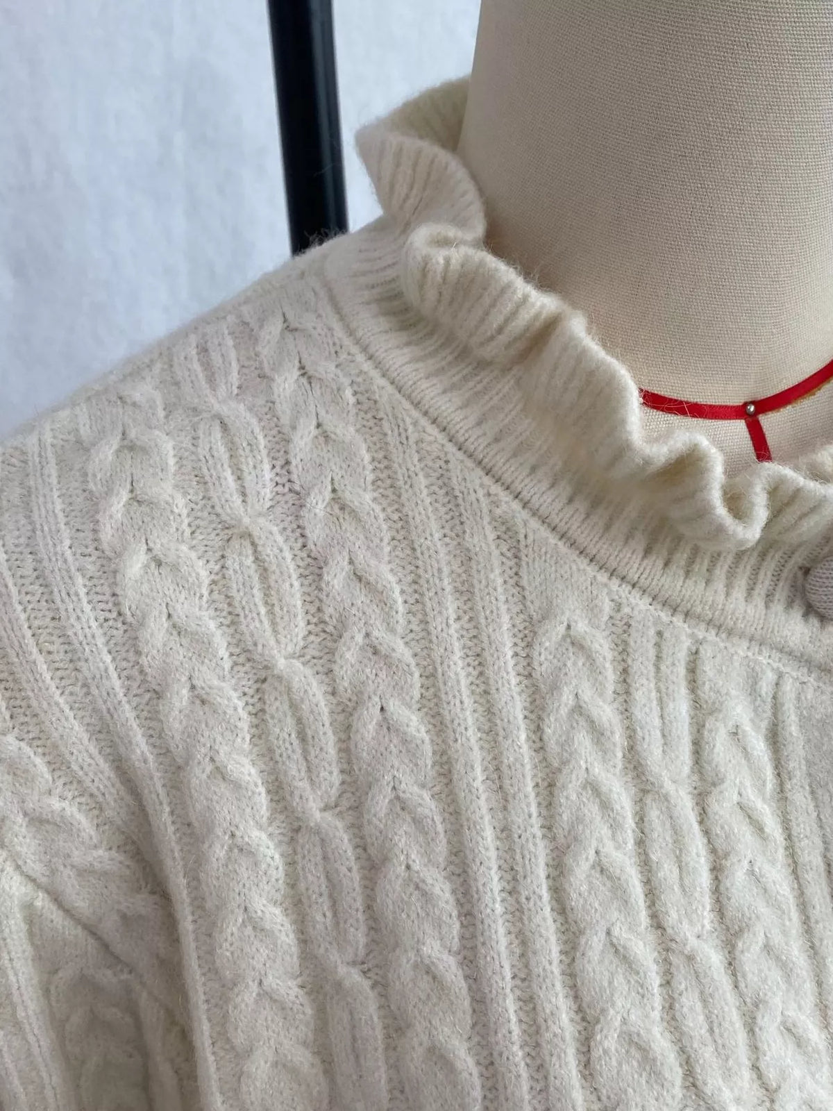 Ivory cable-knit ruffle-trim cardigan, ruffled collar detail.
