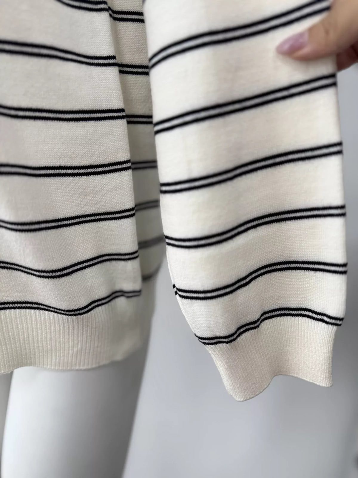 Striped crewneck sweater with layered tie detail in white and black, hem close-up
