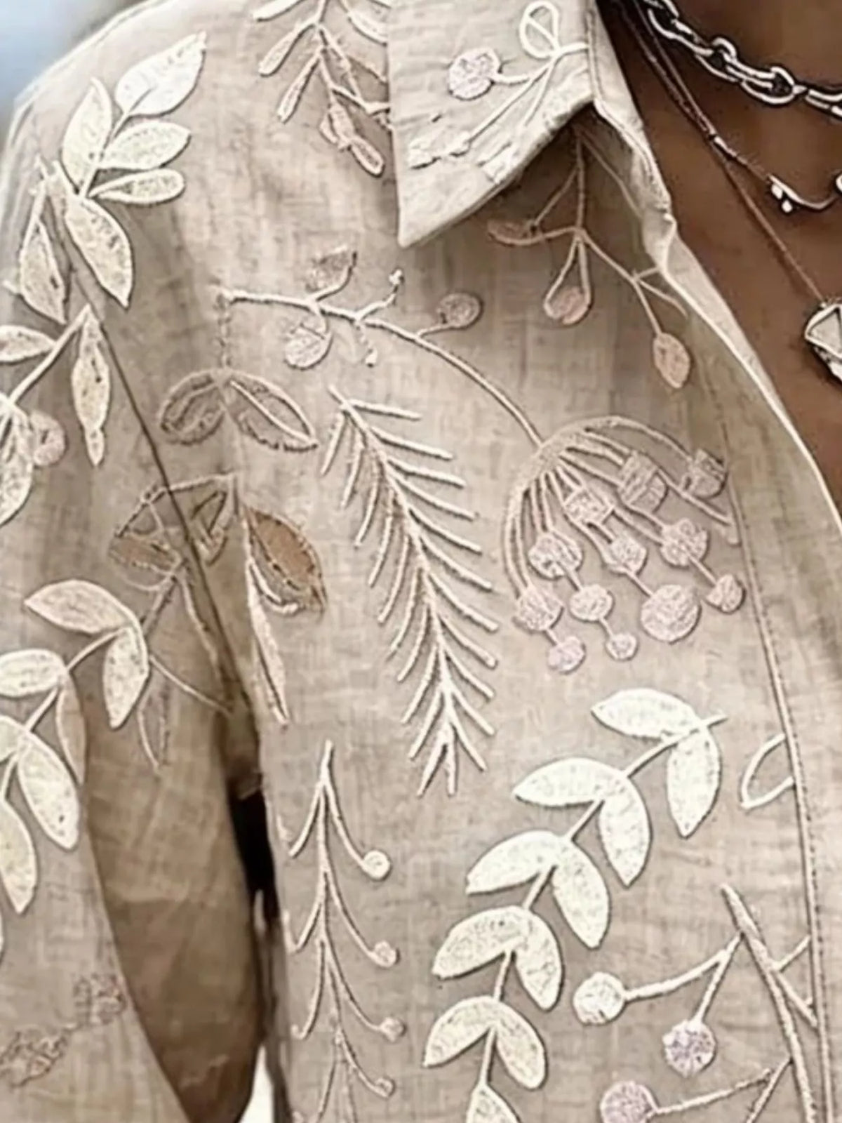 Beige leaf-embroidered button-down shirt, collar and leaf embroidery detail.