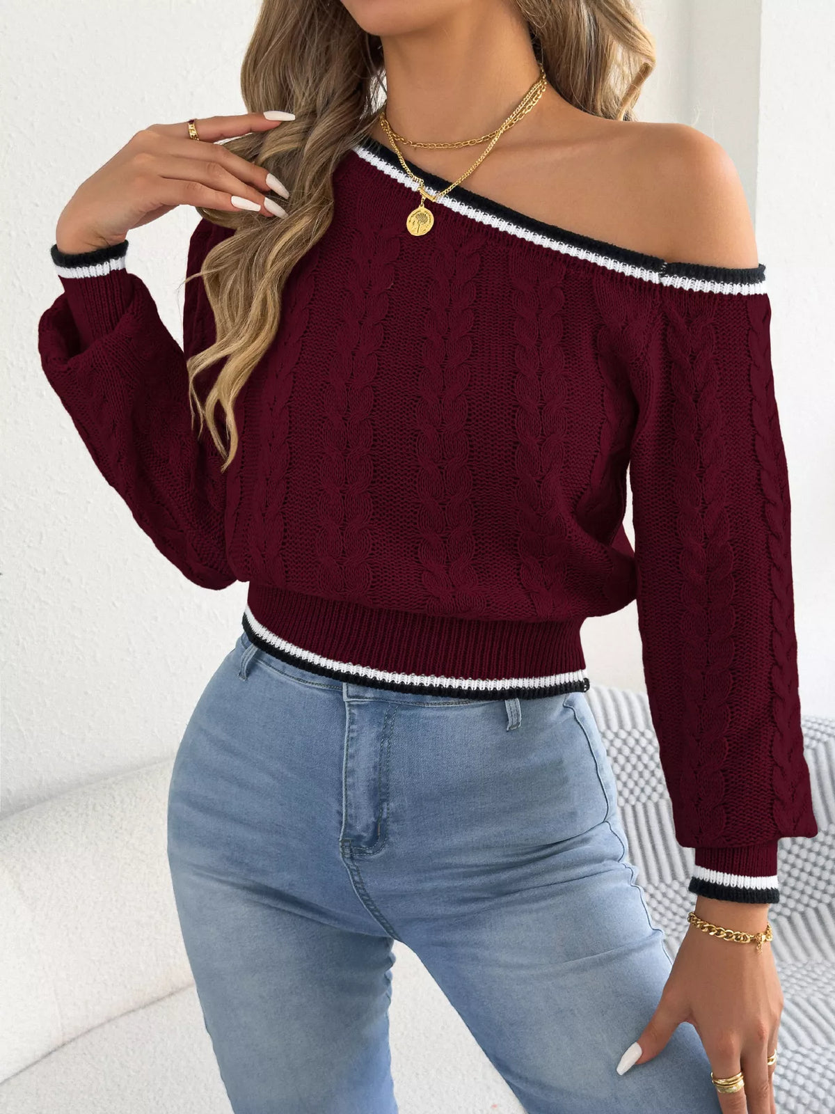 Orange one-shoulder cable knit sweater with striped trim