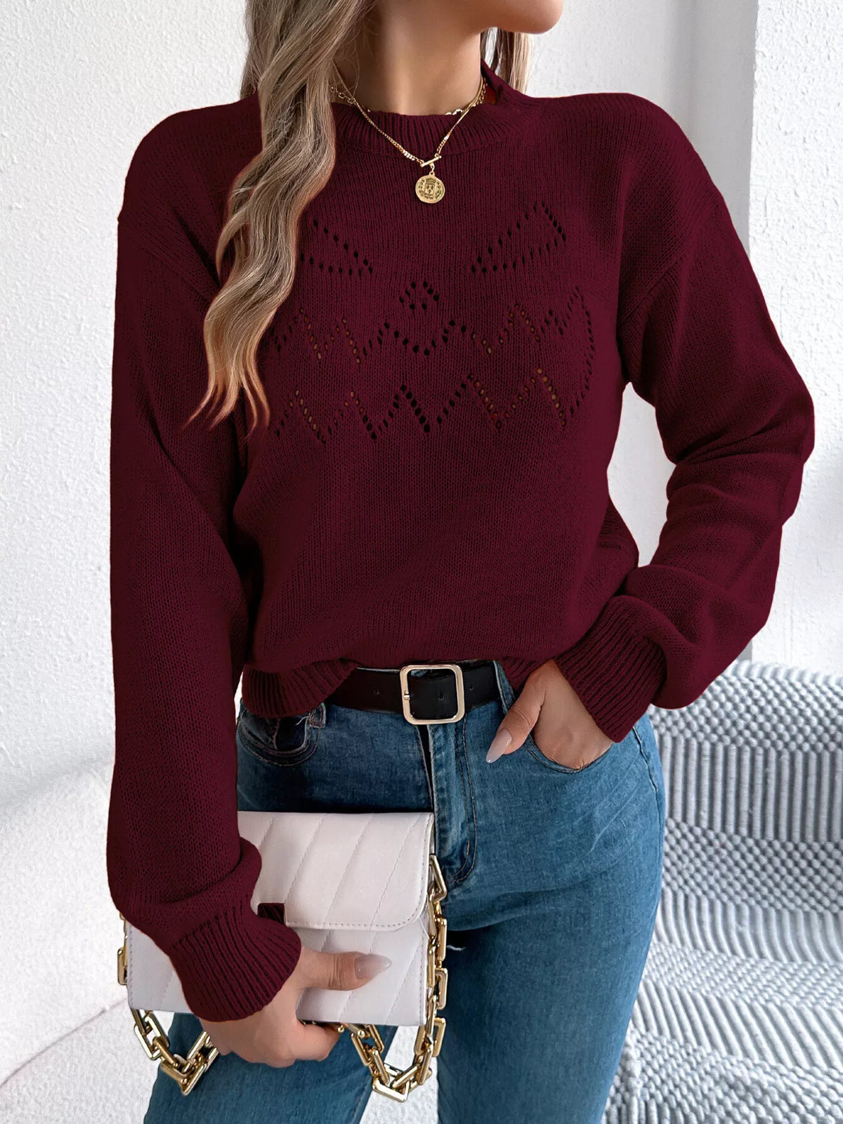 Burgundy halloween pumpkin face knit sweater, front with handbag.