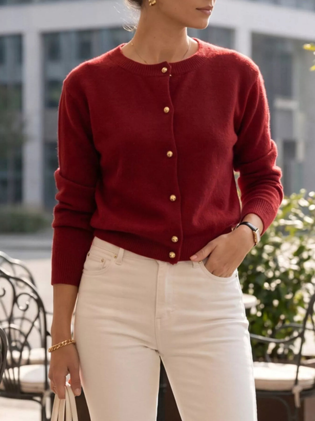 Burgundy round-neck button-front knit cardigan, front view with hand at waist.