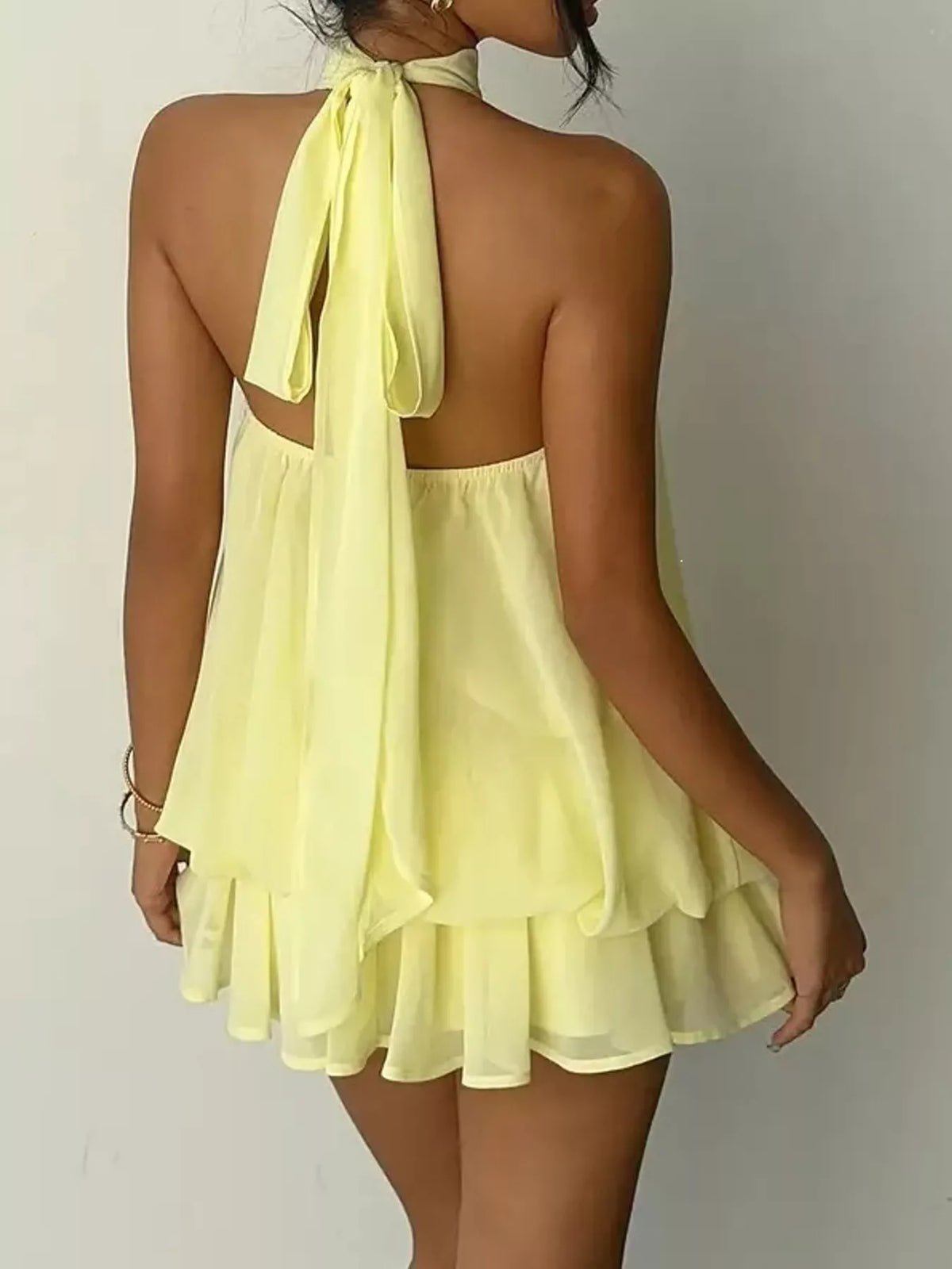 Yellow halter neck layered mini dress, back tie view