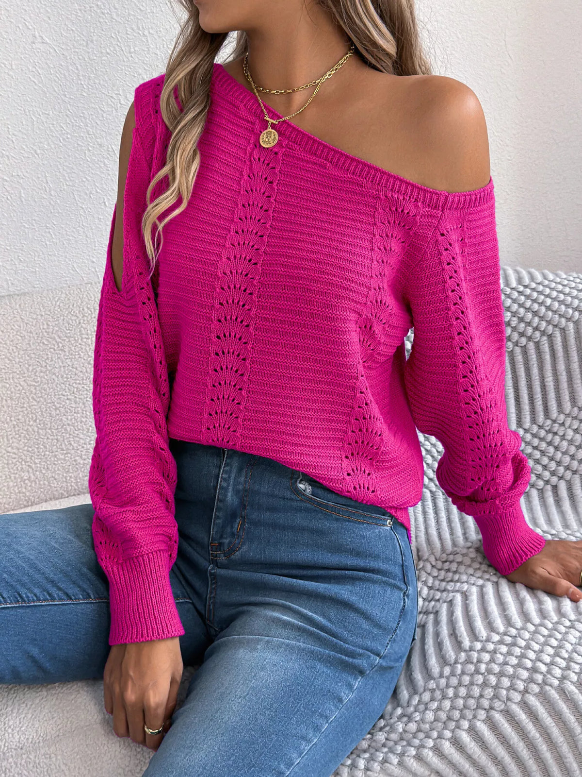 Cerise cold-shoulder openwork knit sweater, seated front view.