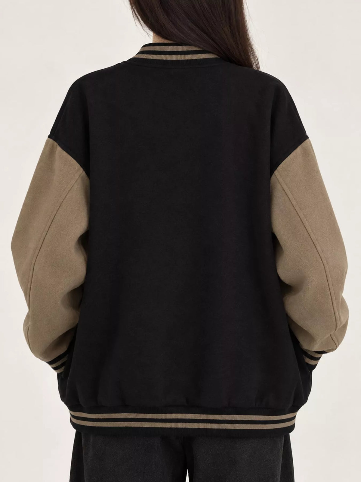 Black and beige color-block varsity bomber jacket, back view