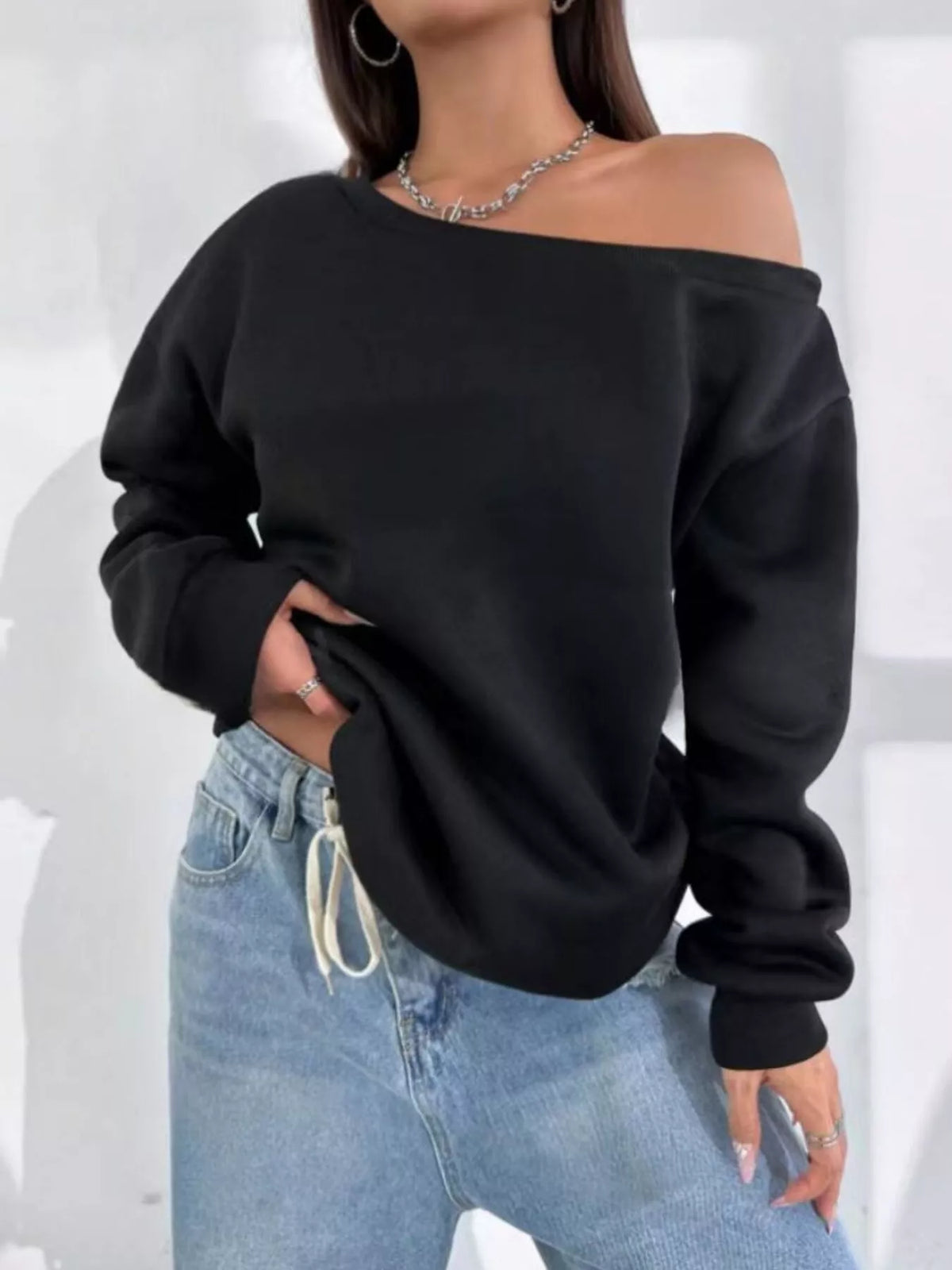 Black asymmetric-neck sweatshirt, front view with hand at hip