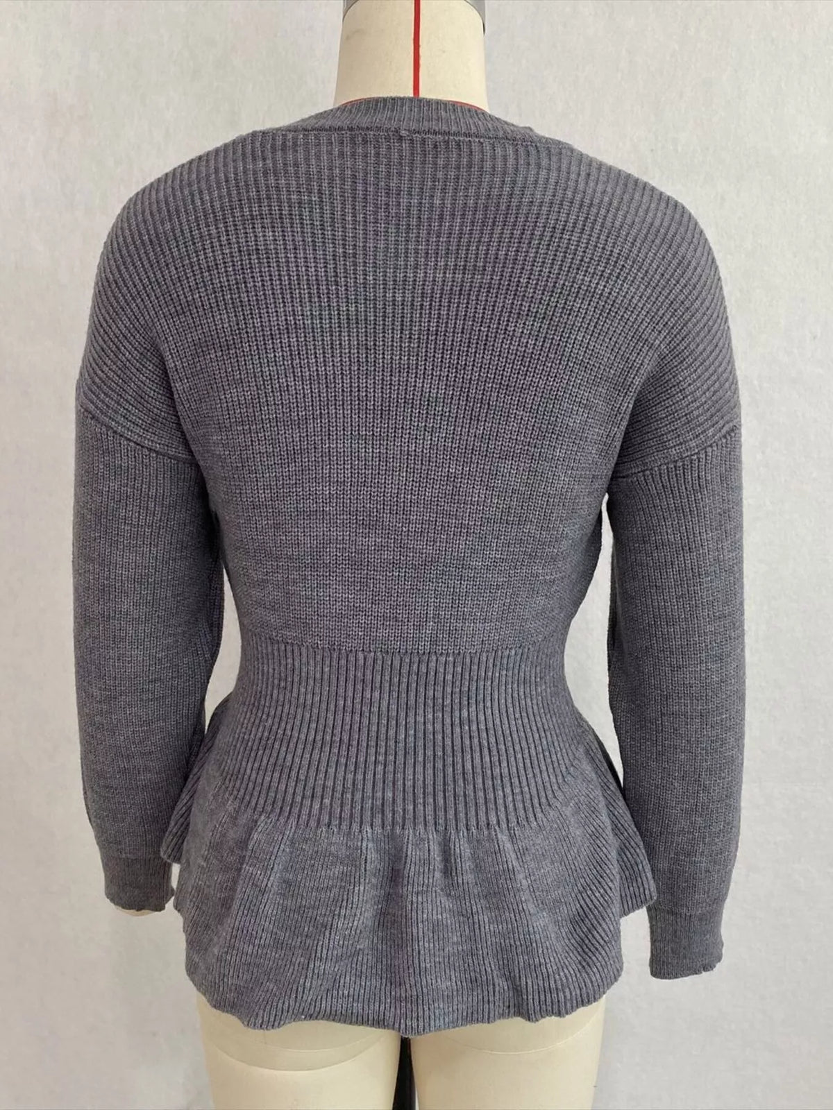 Gray v-neck peplum-hem knit sweater, back on dress form.