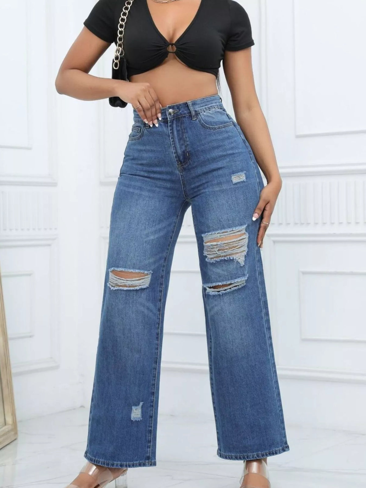 Dark blue distressed wide-leg jeans, front view with hand at waist