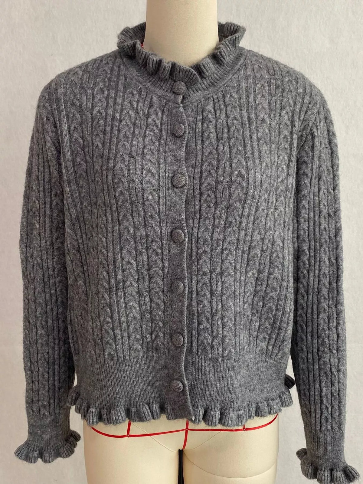 Gray cable-knit ruffle-trim cardigan, front on dress form.