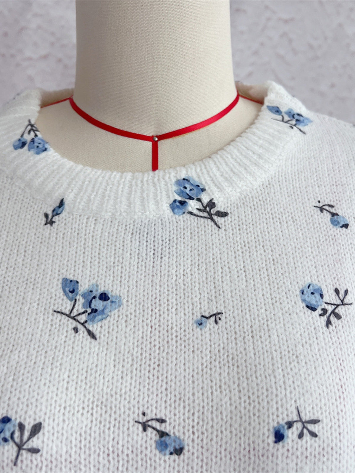 White floral dropped-shoulder oversized sweater, neckline close-up.