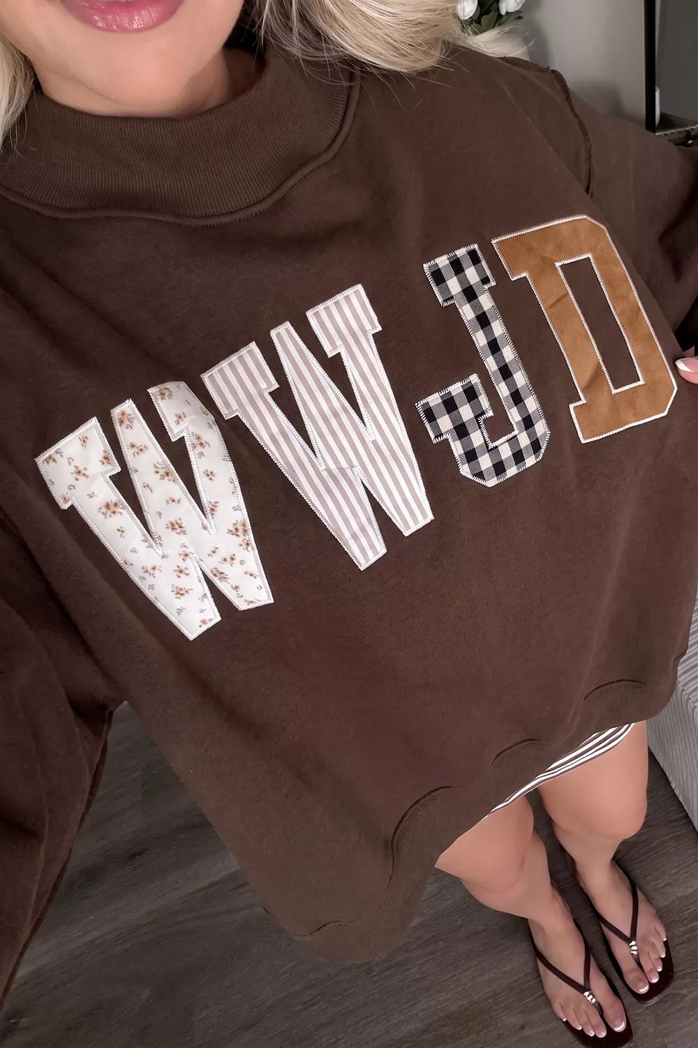 Brown wwjd patchwork graphic mock-neck sweatshirt, graphic viewed from above.