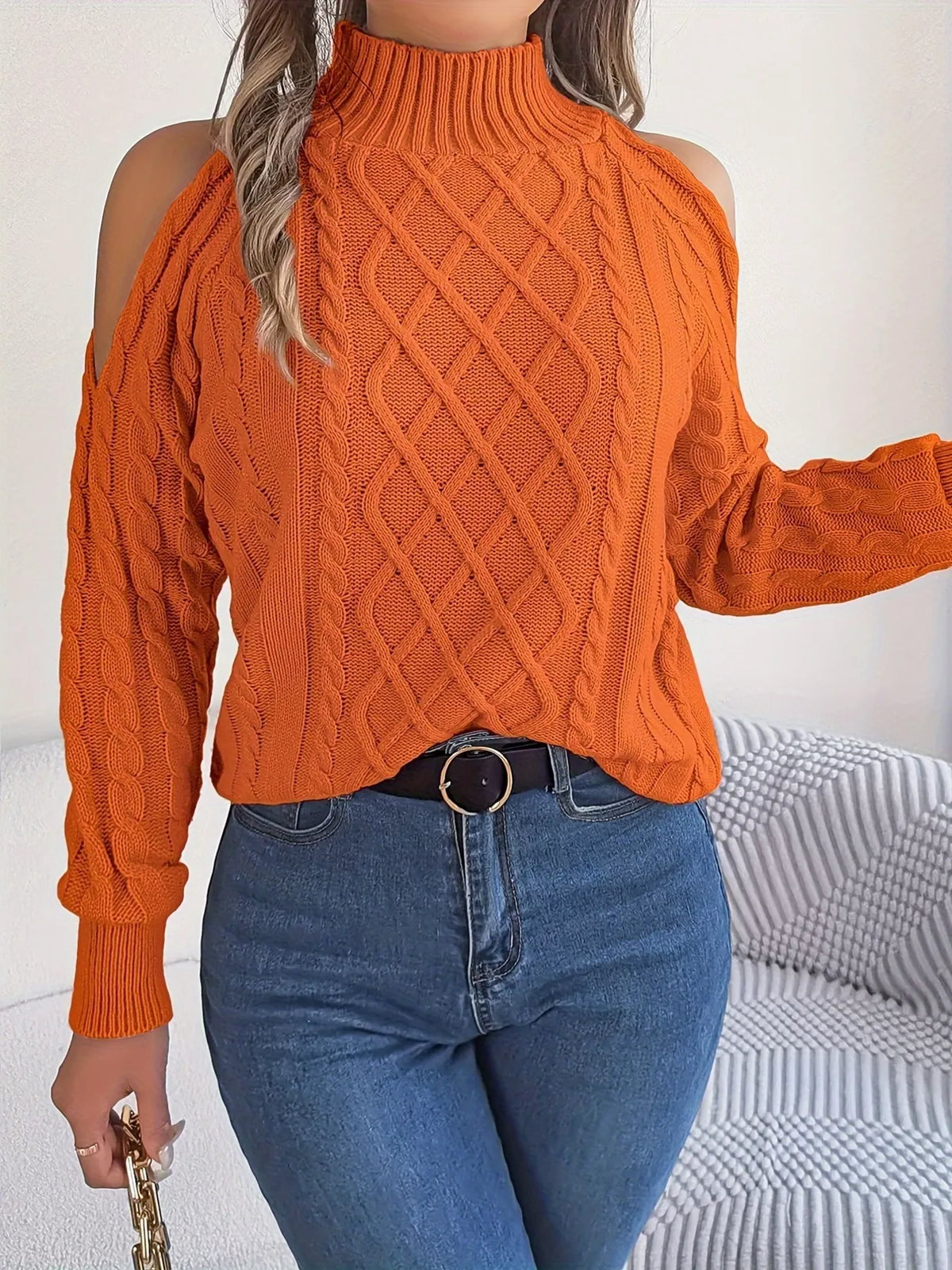 Orange cold-shoulder cable-knit sweater, front with raised arm.