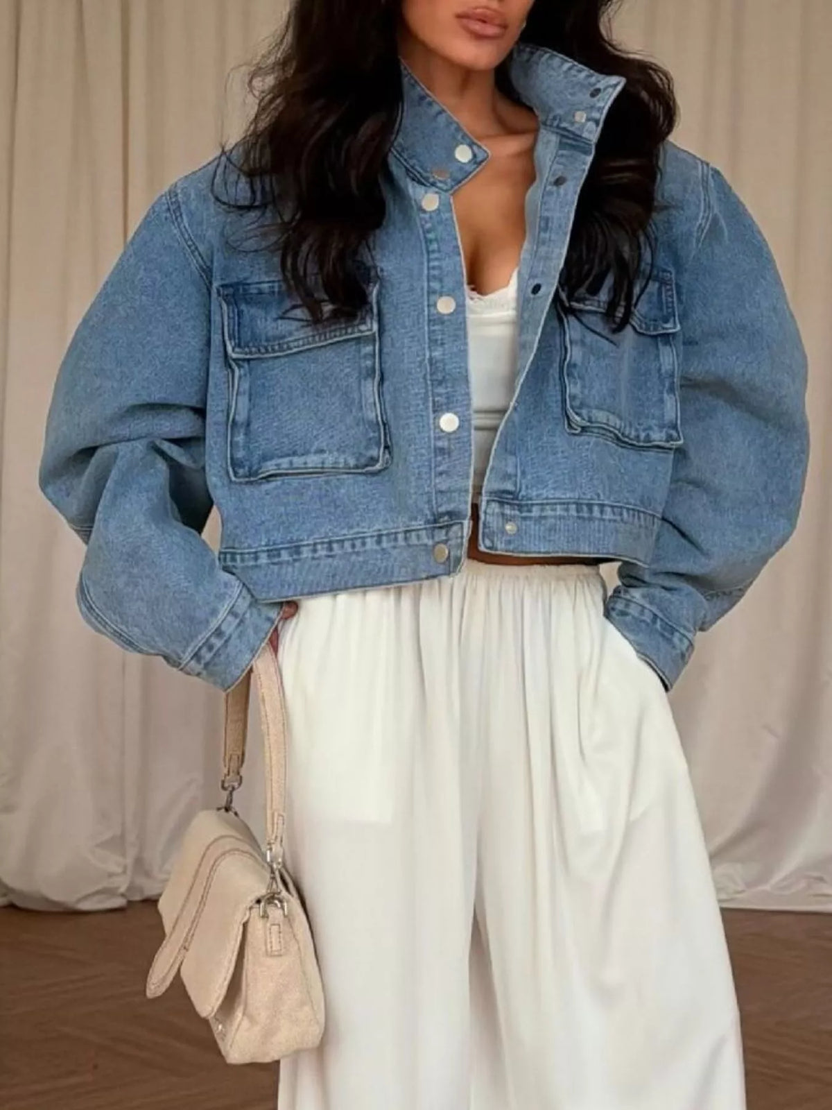 Blue oversized cropped denim utility jacket, front view with hands at waist.