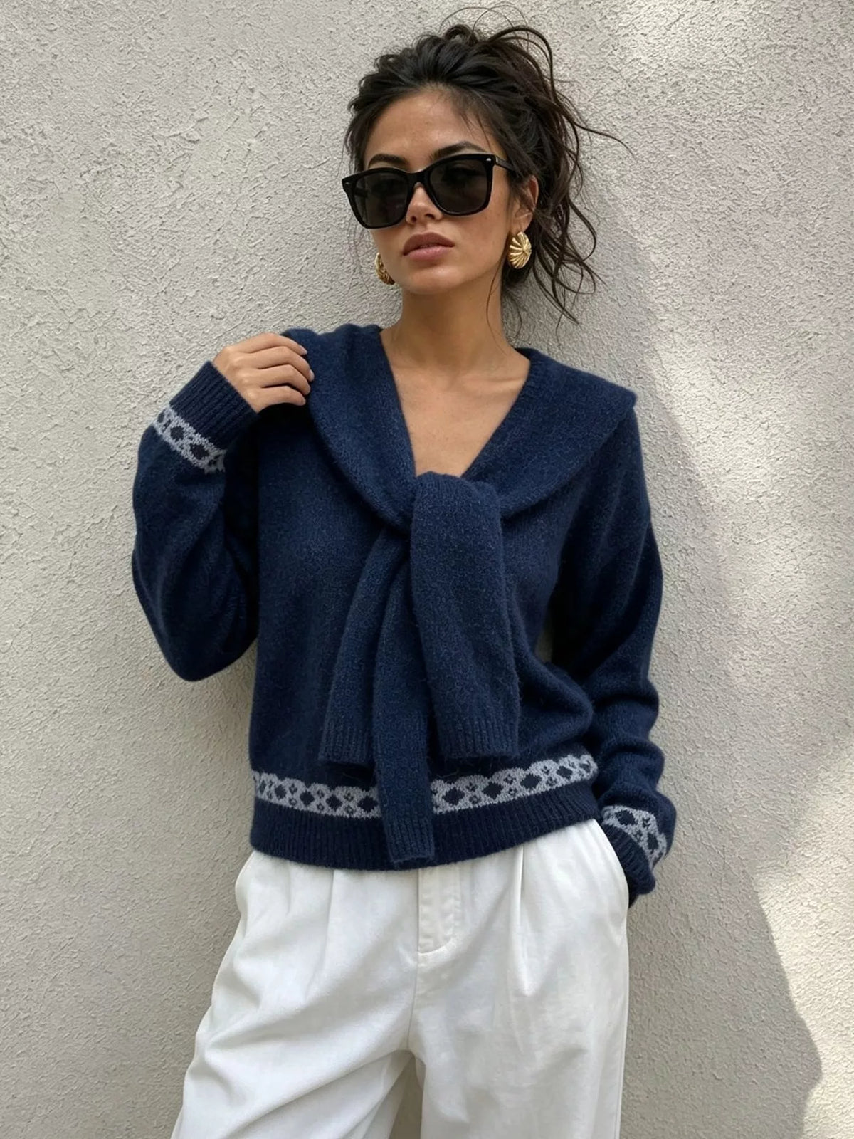 Navy scarf-detail dropped-shoulder sweater, front with hand at scarf.
