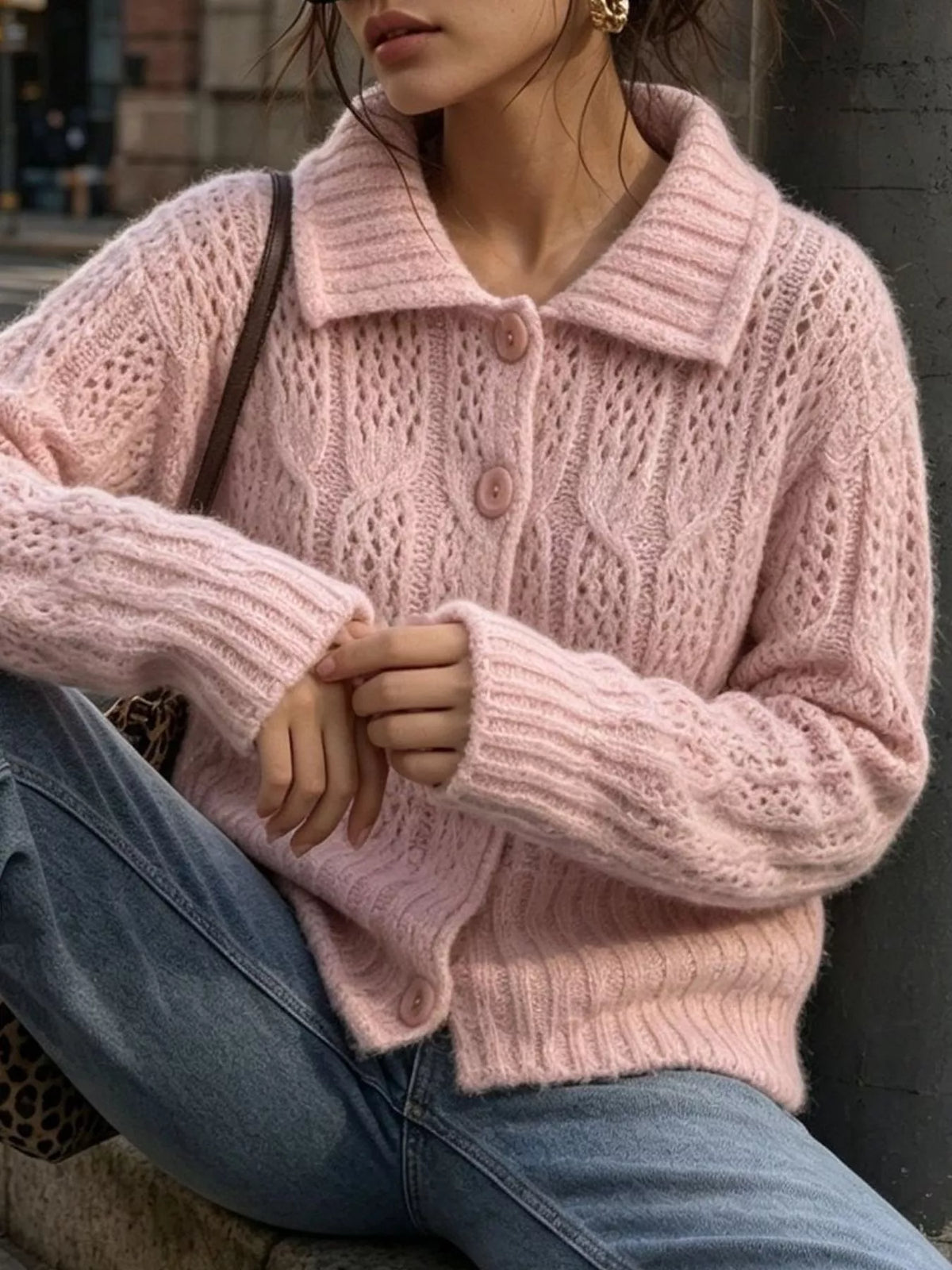 Pink cable-knit collared button-front cardigan, seated front view.