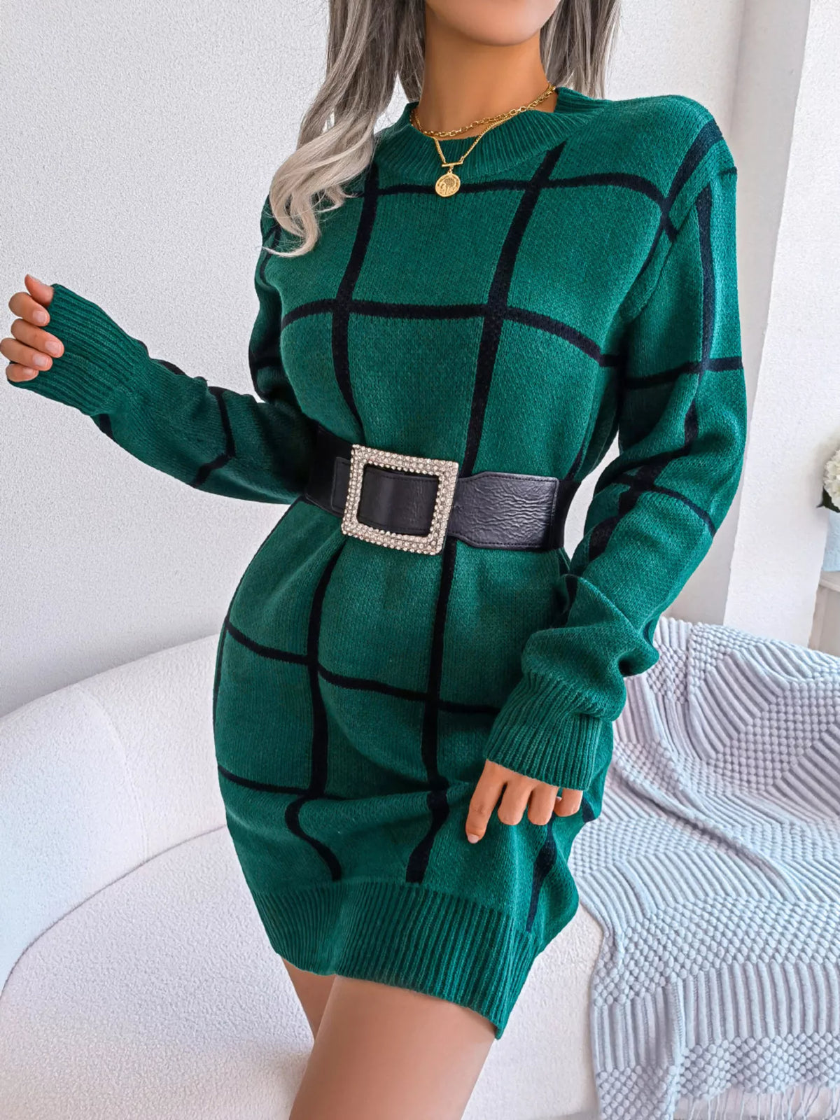 Green windowpane long-sleeve sweater dress, belted front with arm extended.