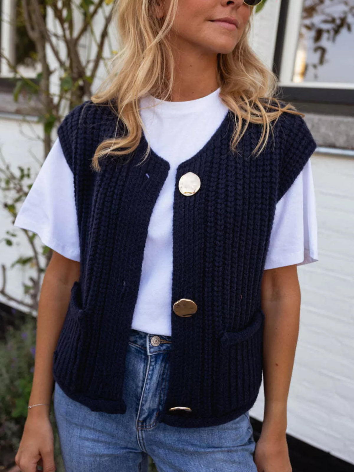 Navy button-front knit sweater vest, front view layered over a white shirt.