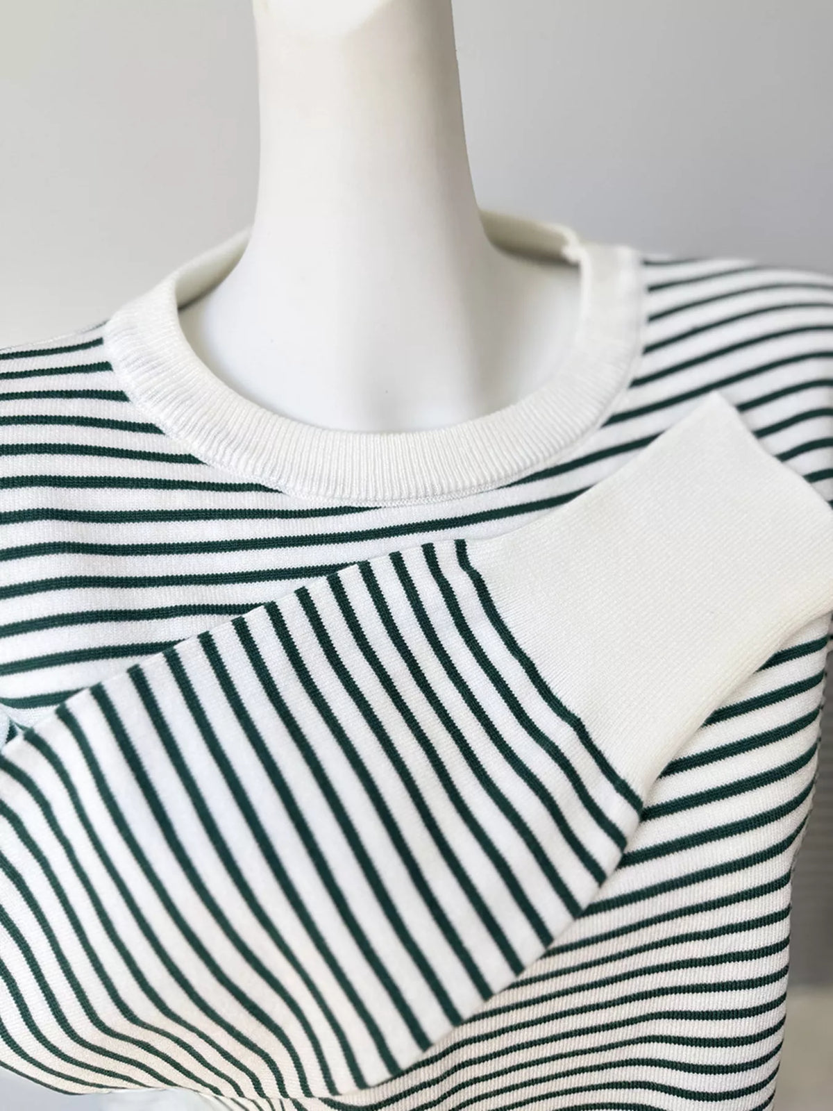 Striped round-neck knit top in white and green, folded cuff detail