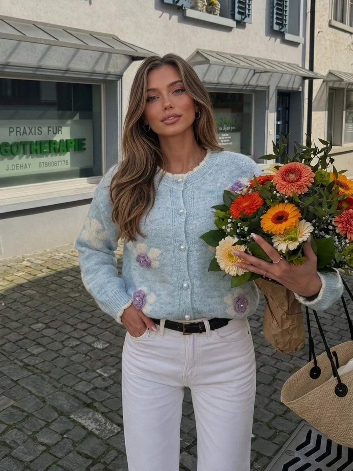Floral-applique knit cardigan in light blue, front view holding flowers