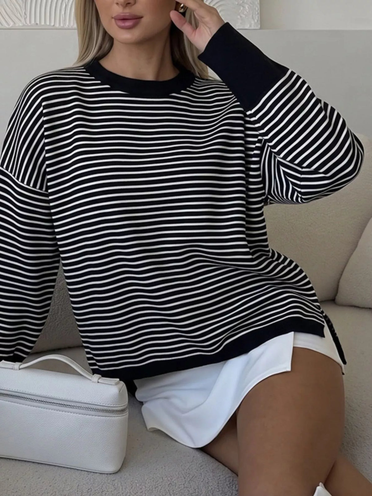 Striped round-neck knit top in black and white, seated view