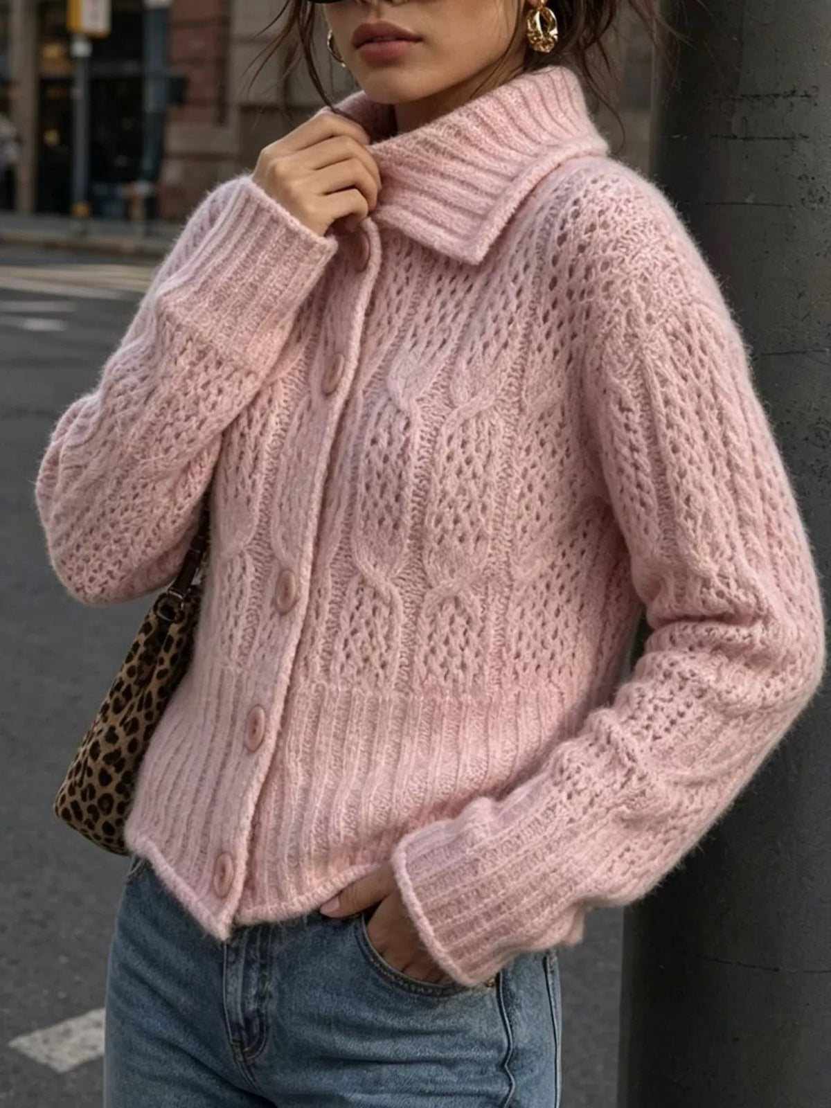 Pink cable-knit collared button-front cardigan, front holding collar.
