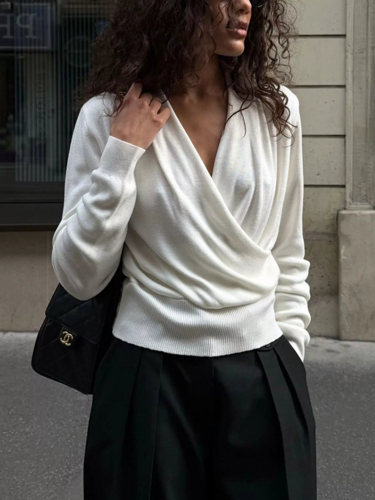 White wrap-front sweater, front view with hand at neckline
