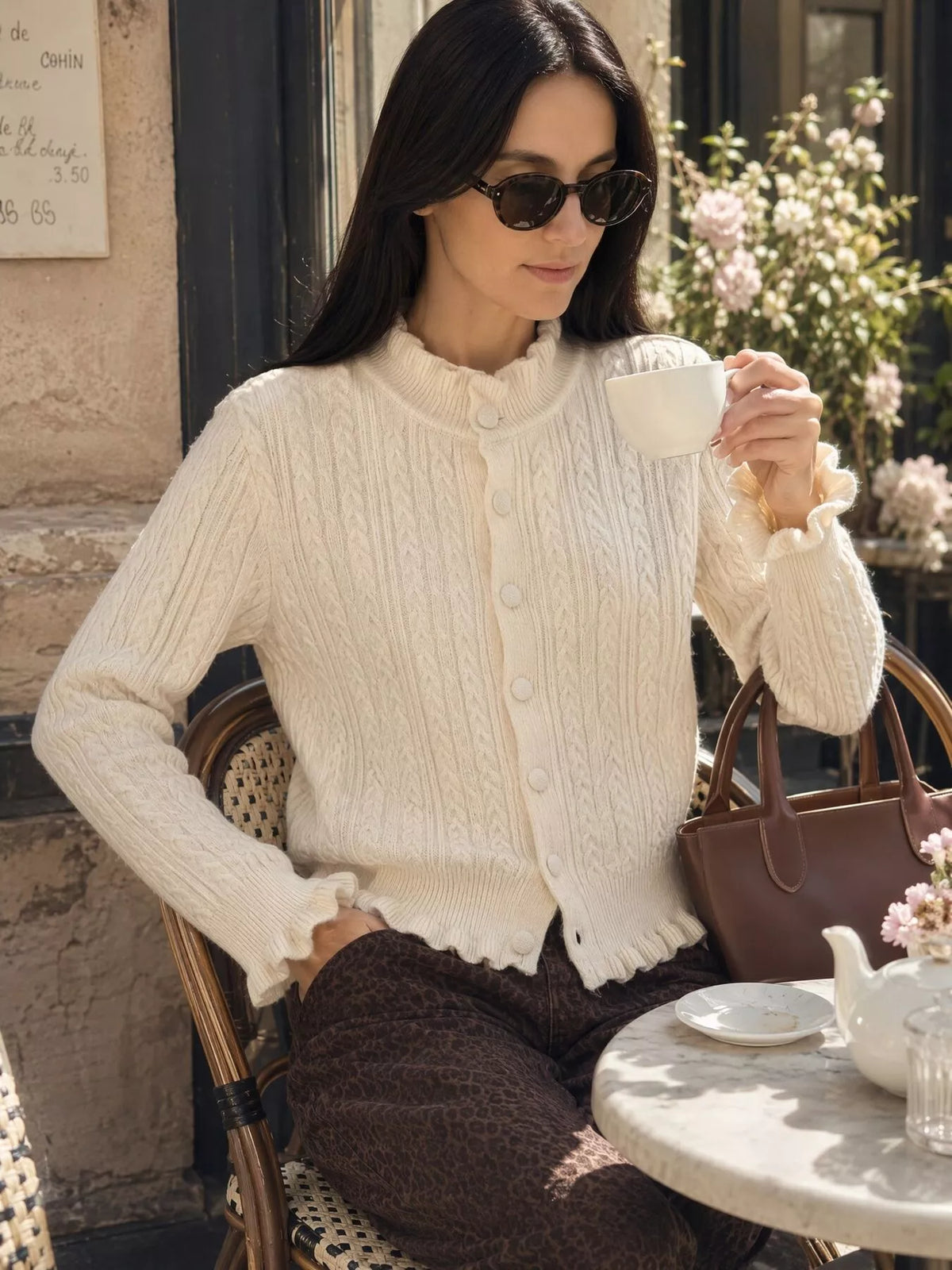 Ivory cable-knit ruffle-trim cardigan, seated front view.