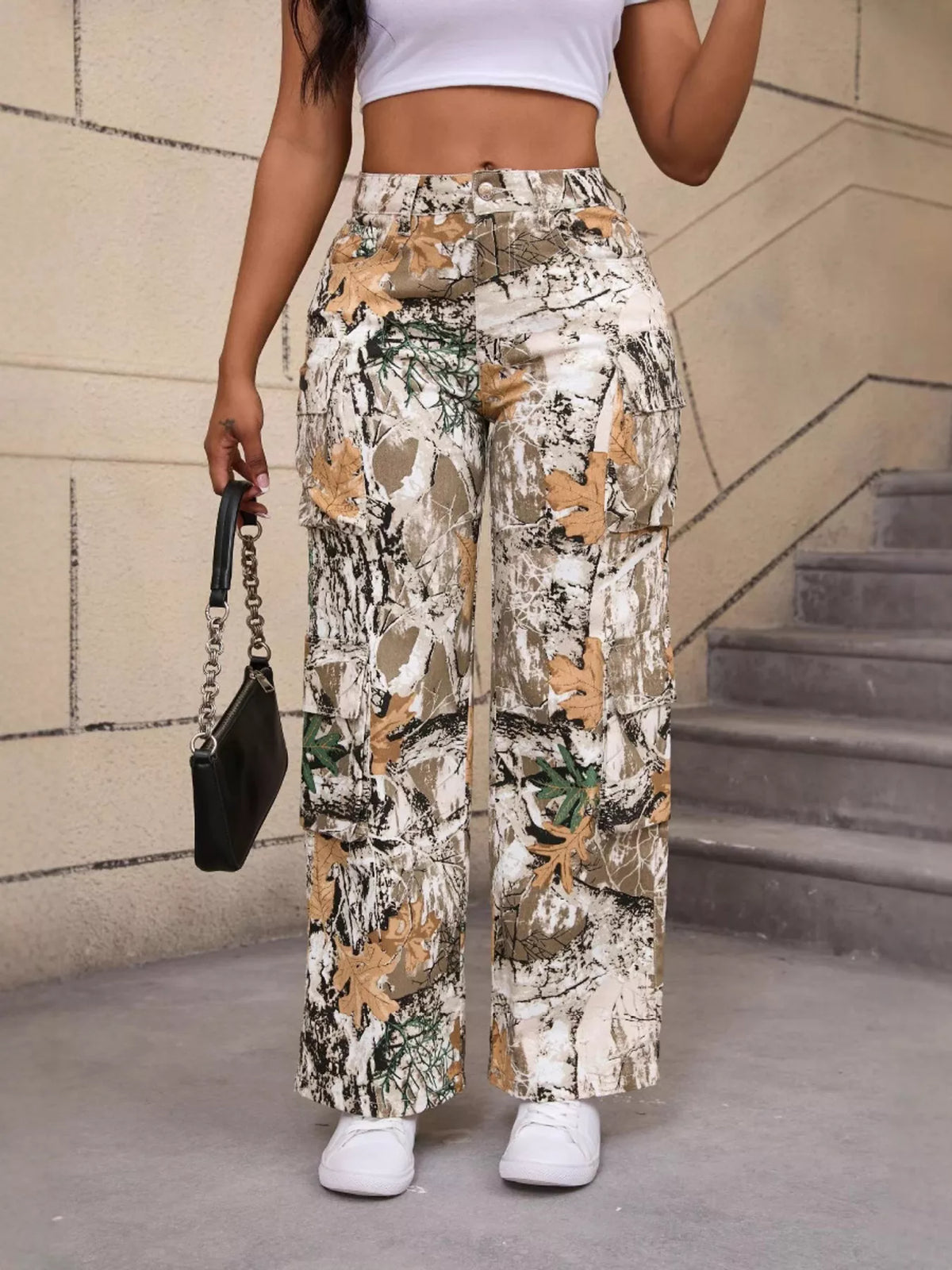 Beige and green high-waisted camouflage cargo pants, front view with raised hand.